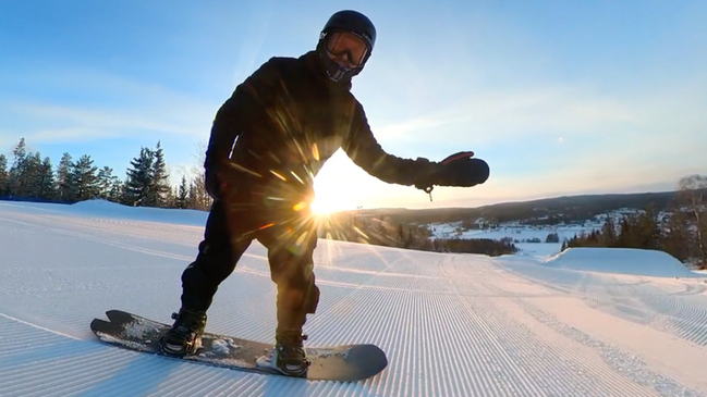 Bild som visar en person som vinkar och åker snowboard i
Sidsjöbacken i Sundsvall. Foto: Magnus Westman